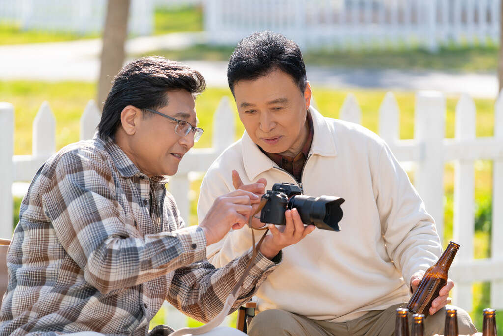 两个老年男人坐在露营地看数码相机图片