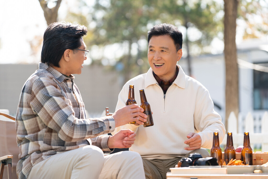 两个老年男人坐在露营地喝啤酒