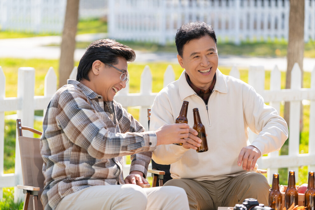 两个老年男人坐在露营地喝啤酒