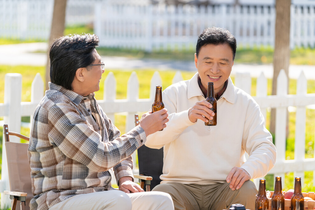 两个老年男人坐在露营地喝啤酒