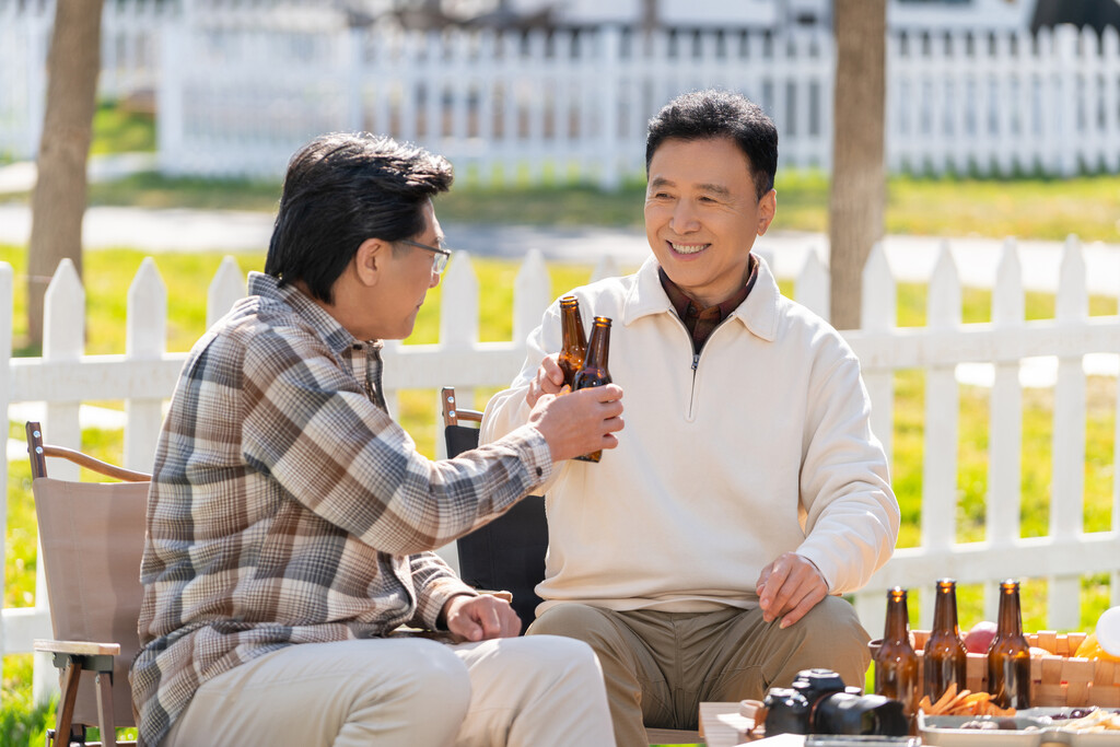 两个老年男人坐在露营地喝啤酒