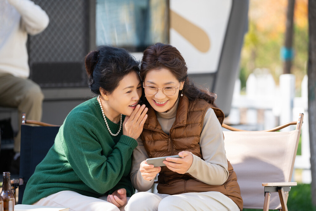 两个老年人女人坐在露营地聊天看手机视频图片