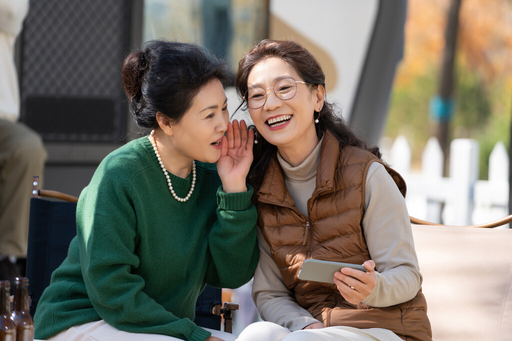 两个老年人女人坐在露营地聊天看手机视频图片