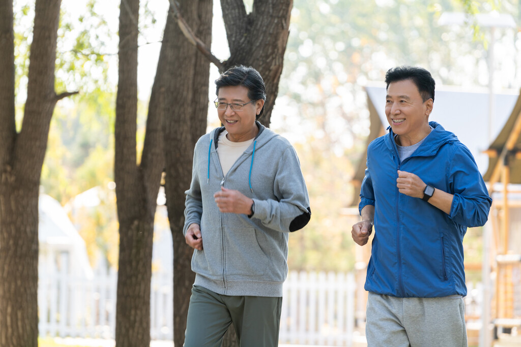 两戴运动手表的中老年男人在树林里跑步健身