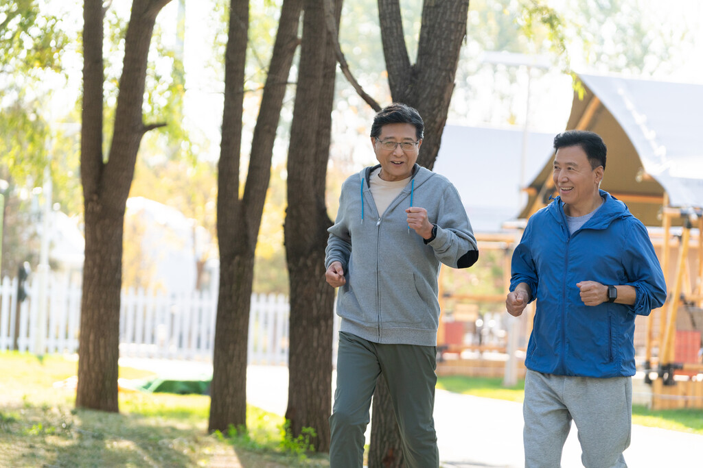 两戴运动手表的中老年男人在树林里跑步健身