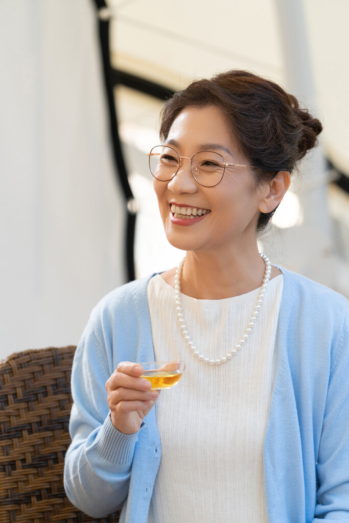 一个中老年女人在露营地坐着摇椅喝茶图片