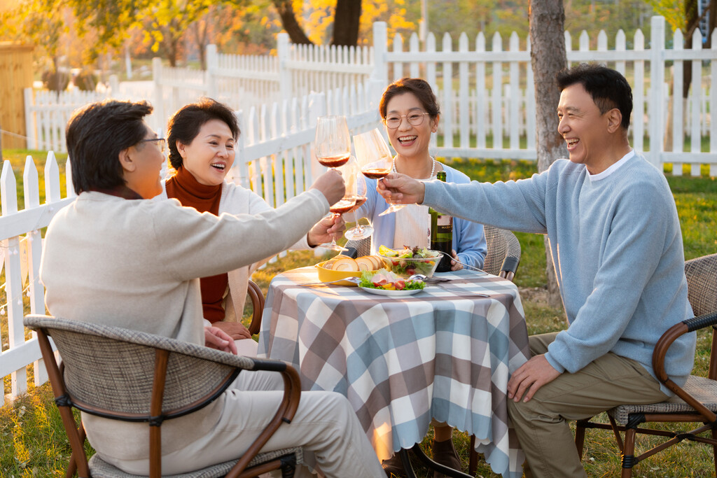 夕阳下中老年朋友在庭院里聚会喝酒聊天图片