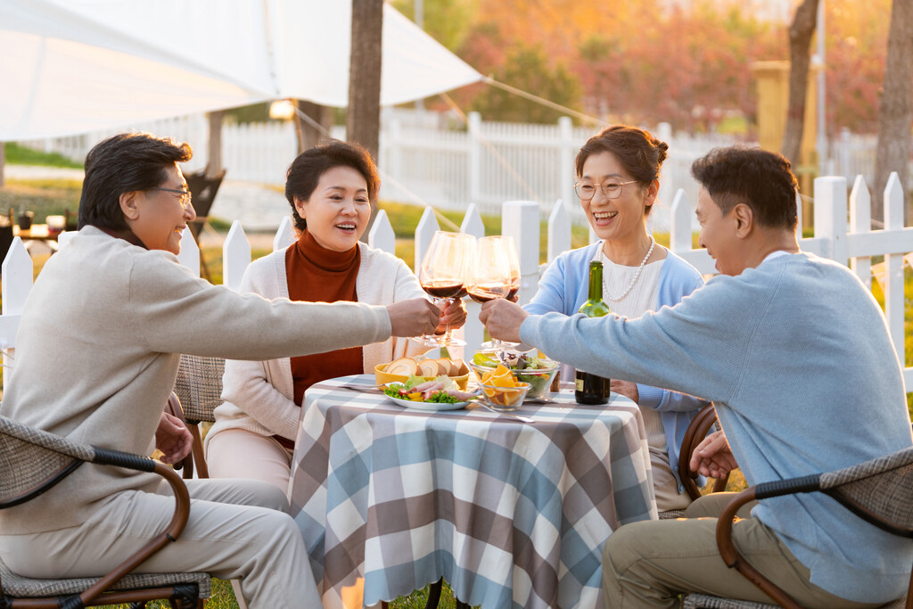 夕阳下中老年朋友在庭院里聚会喝酒聊天图片