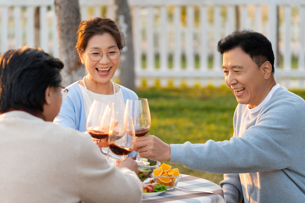 夕阳下中老年朋友在庭院里聚会喝酒聊天图片