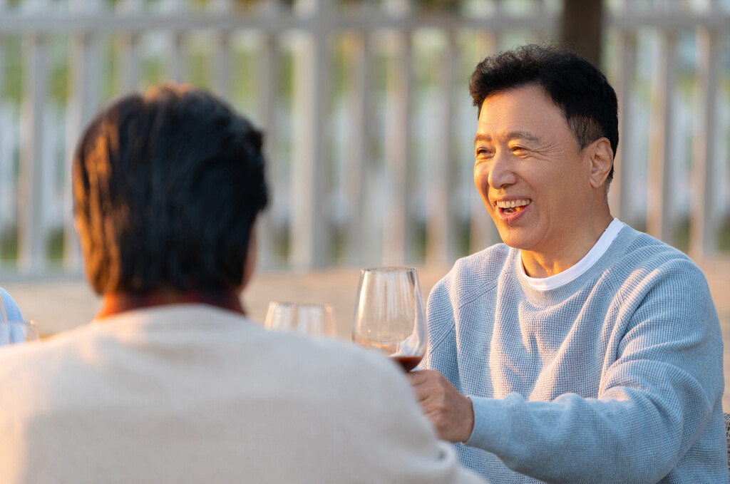 夕阳下中老年朋友在庭院里聚会喝酒聊天