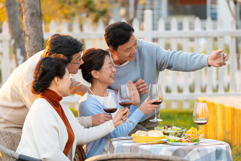 夕阳下中老年朋友在庭院里聚会喝酒拍照片图片